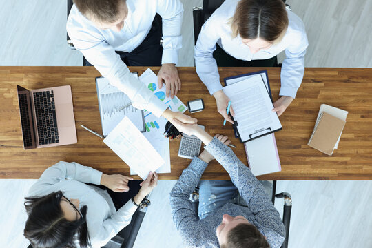 Group Of People Sitting At Table And Shaking Hands Top View