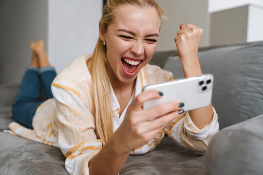 Woman making winner gesture while playing online game on cellphone
