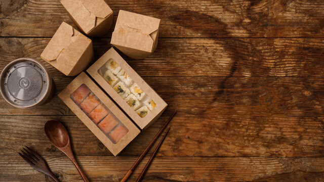 Asian food delivery. Packaging for sushi and woks. Food in paper containers on wooden background