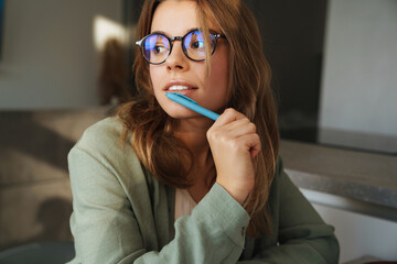 Focused nice student woman thinking while sitting at table in home