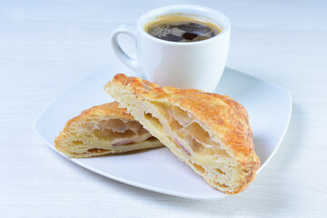 Cup of Colombian coffee, accompanied by baked bakery on white wooden background