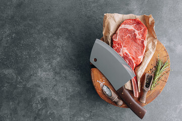 on a wooden block for meat a fresh raw tamahawk steak or a cowboy steak with a butcher's chopping...