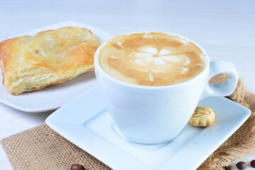 Cup of Colombian coffee, accompanied by baked bakery on white wooden background