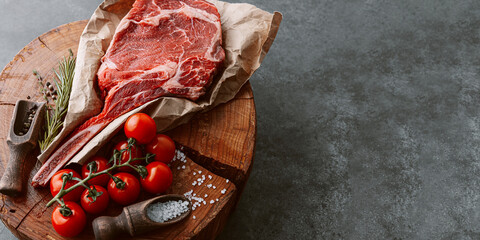 fresh raw cowboy tomahawk steak on a round wooden cutting board for meat