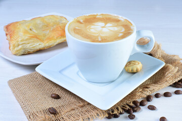 Cup of Colombian coffee, accompanied by baked bakery on white wooden background