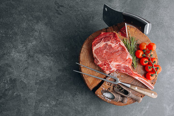 on a wooden block for meat a fresh raw tamahawk steak or a cowboy steak with a butcher's chopping...