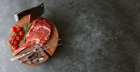 on a wooden block for meat a fresh raw tamahawk steak or a cowboy steak with a butcher's chopping...
