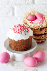 Easter composition with wicker basket with pink colored eggs and decorated Easter cake