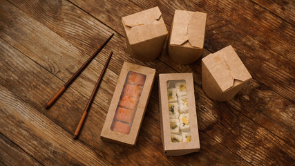 Asian food delivery. Packaging for sushi and woks. Food in paper containers on wooden background