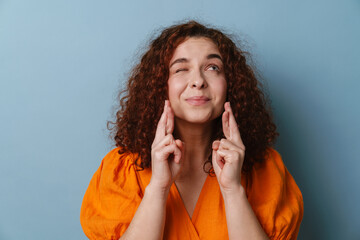 Happy ginger woman winking and holding fingers crossed for good luck
