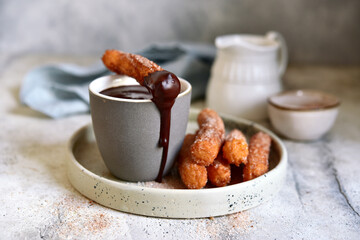Traditional spanish dessert churros - fried choux pastry with chocolate sauce.
