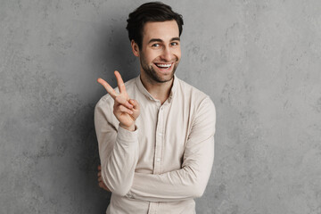 Joyful handsome guy smiling and showing peace sign