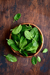 Fresh organic spinach leaves in a wooden bowl . Top view with copy space.