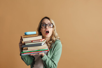 Shocked beautiful woman in eyeglasses posing with books and planners