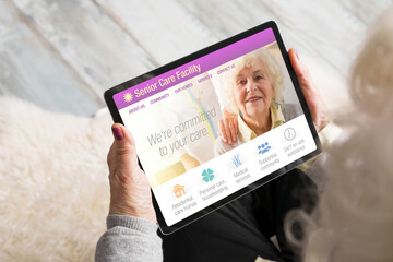 Senior woman looking at senior care facility website on tablet computer