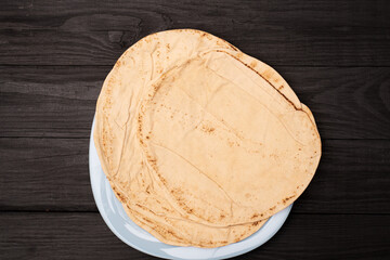 Round pita bread on a dark wooden background.