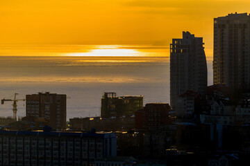 Bright orange sunset in Vladivostok. Silhouettes of new residential buildings against the backdrop of a bright sunset.