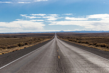 Fototapeta na wymiar Empty two lane highway cutting through open desert in rural New Mexico on clear day