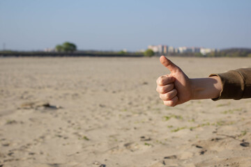 Clean sandy beach, fight for the environment. The concept of protecting the environment from pollution. Children's hand on the river bank shows a positive sign