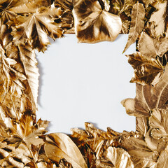 White card note with frame of golden leaves. Top view of frame made of golden colored leafs with square paper note in the middle with copy space for text or product