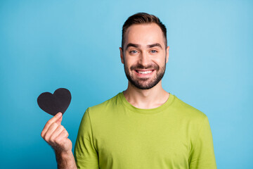 Photo of handsome bearded man hold paper heart charming smile wear green t-shirt isolated blue color background