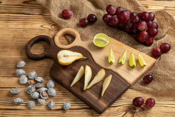 Cheese, grapes, lime, pear and nuts on a cutting board