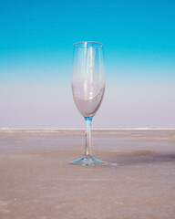 Empty glass goblet on beige surface against blue sky background