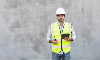 Hispanic or Middle Eastern people. Portrait Of Construction Worker holding red radio and digital tablet isolate on gray cement background. Project engineer On Building Site.