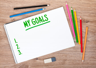 Goals list and colorful pencils on the wooden table