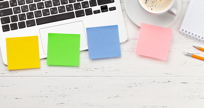 Office desk with colorful stickers, coffee and laptop