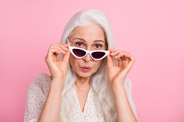 Close-up portrait of attractive amazed grey-haired woman touching specs pout lips isolated over pink pastel color background