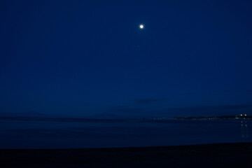 Fototapeta na wymiar 春の夜の海に昇る満月 