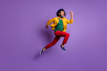 Fototapeta na wymiar Full length photo of funky dark skin guy dressed yellow shirt headwear jumping running fast isolated purple color background