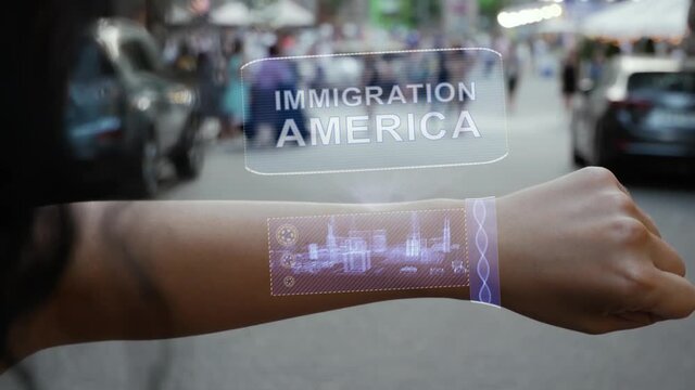 Female hand activates conceptual HUD holograms on smart bracelet with text Immigration America. Unrecognizable woman with holographic technology on a city street background