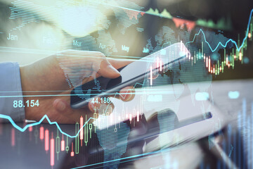Online trading business concept with man hand using smartphone and transparent digital display with stock market graphs and diagram