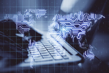 Big data concept with human hand typing on laptop keyboard ans abstract digital microchip world map