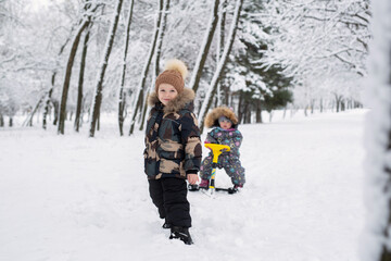 Naklejka premium Small boy pulls his little sister on a sled.