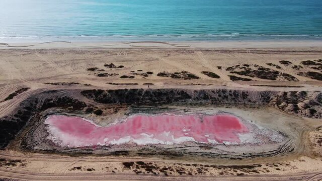 Pink lake in Ras al Khaimah surrounded by seaside, desert sand and mountains in the UAE