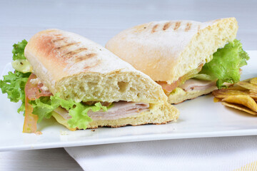 Ham, cheese and lettuce sandwich on white wooden background