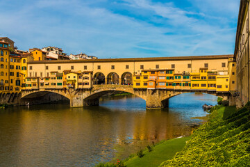 Fototapeta premium Lovely panoramic view of the bridge Ponte Vecchio, famous for the shops built along it over the Arno River in Florence, Italy. The bridge is a medieval stone closed-spandrel segmental arch bridge.