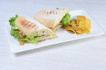 Ham, cheese and lettuce sandwich on white wooden background