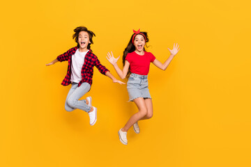 Full size portrait of two excited persons enjoy jumping open mouth isolated on yellow color...