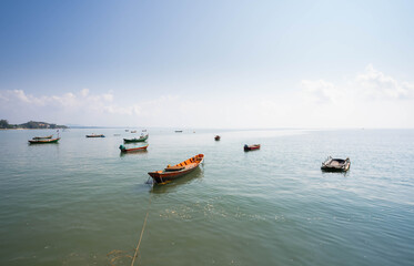 Beautiful blue sky and fishing boat anchored on the shore of the sea in Thailand.