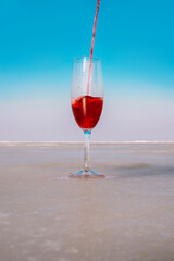 A glass of red wine on ice against a blue sky