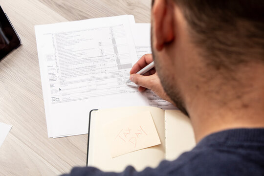 Caucasian man in casual clothes calculating taxes on the tax dial to refund money