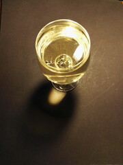 A glass of champagne, wine stands alone on a black background.