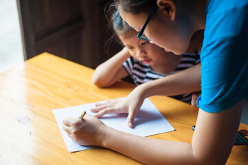 Obraz na płótnie Canvas The teacher is teaching little kids homework and practicing writing letters.