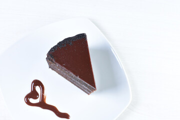 Decorated chocolate cake on white plate and light colored wooden background