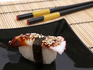 Octopus sushi on black plate on a bamboo mat close-up
