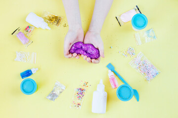 Making slime at home. child stretching colorful slime. DIY concept. hands make slime with sequins on yellow background
